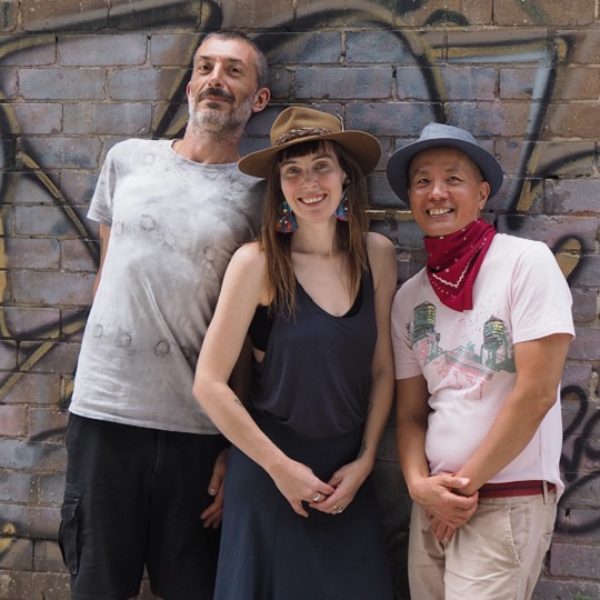Photo of artists against a brick wall. Artsits L-R Alessandro Berini, Selina Springett  and Jayanto Tan